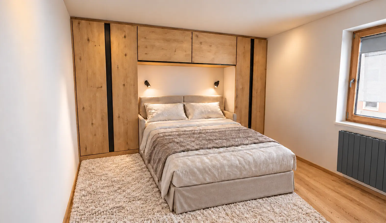 Chambre parents de LAO 1860 : lit double, rangements intégrés en bois clair, deux liseuses et tapis